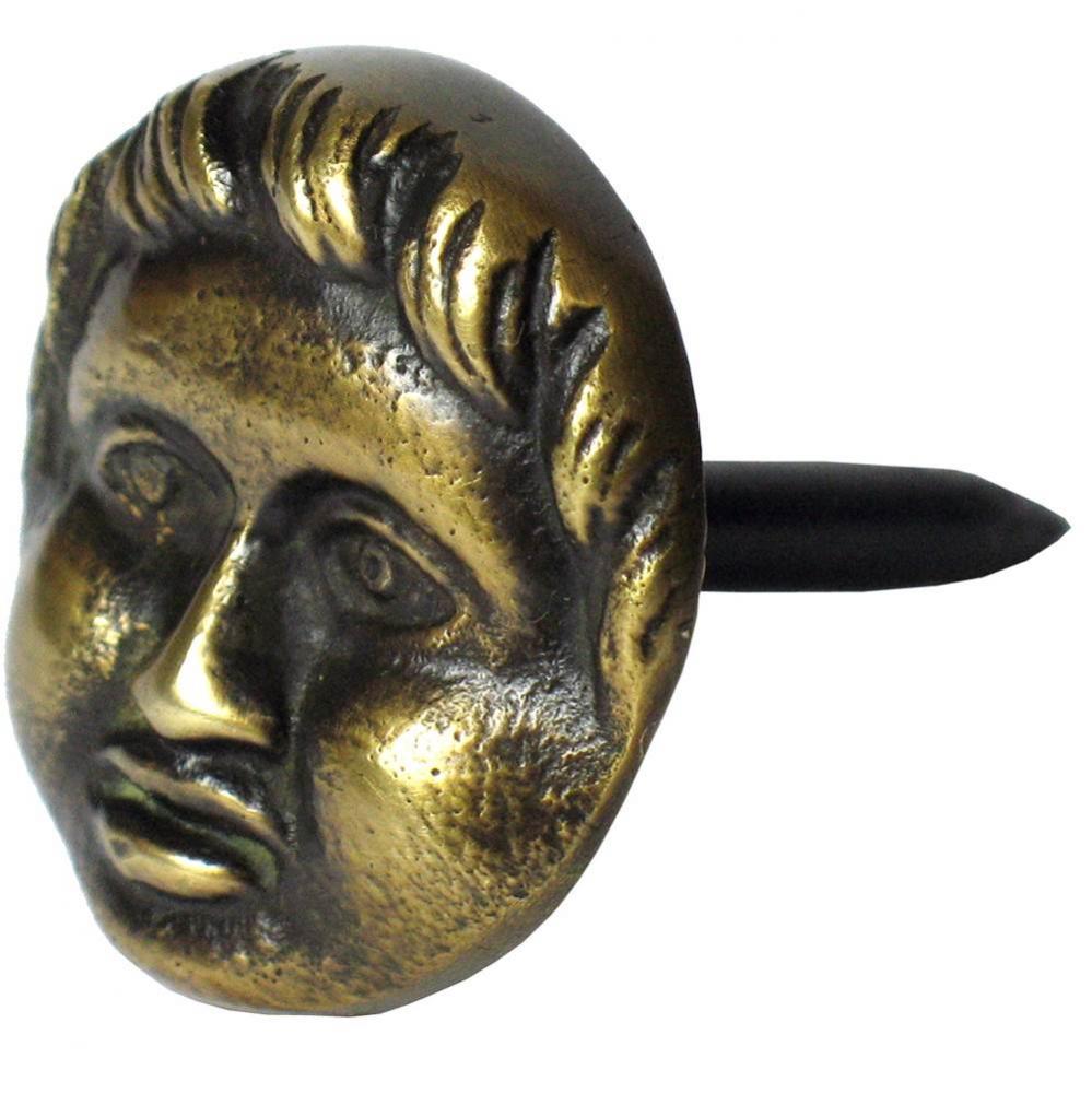 Round brass clavo, human face